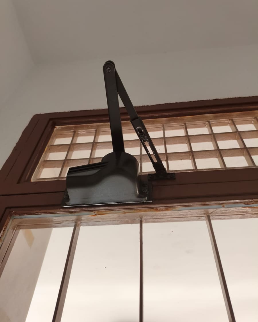Cierrapuertas hidráulico instalado en la puerta de un portal