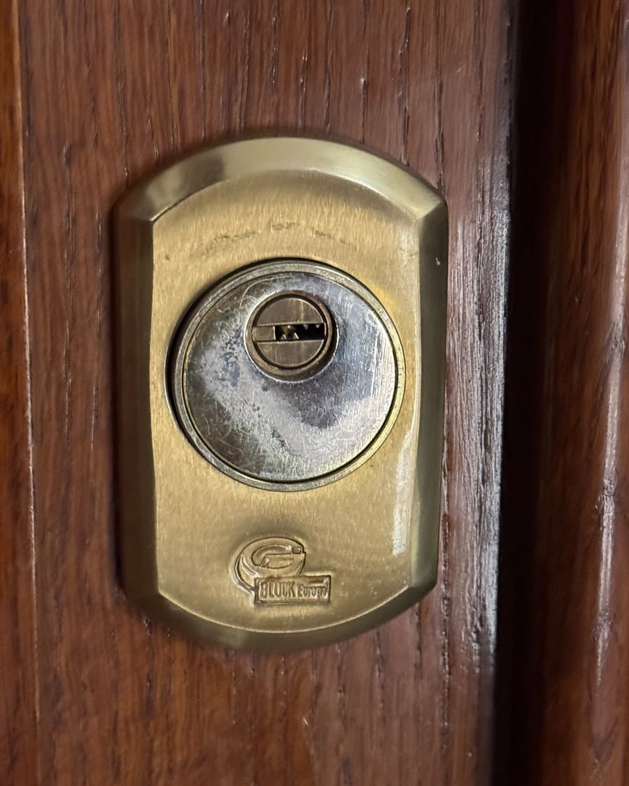 Escudo de latón protegiendo el bombín de una puerta de madera